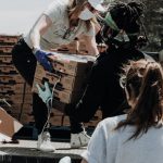 Charity Event - woman in white t-shirt and blue denim jeans sitting on brown cardboard box