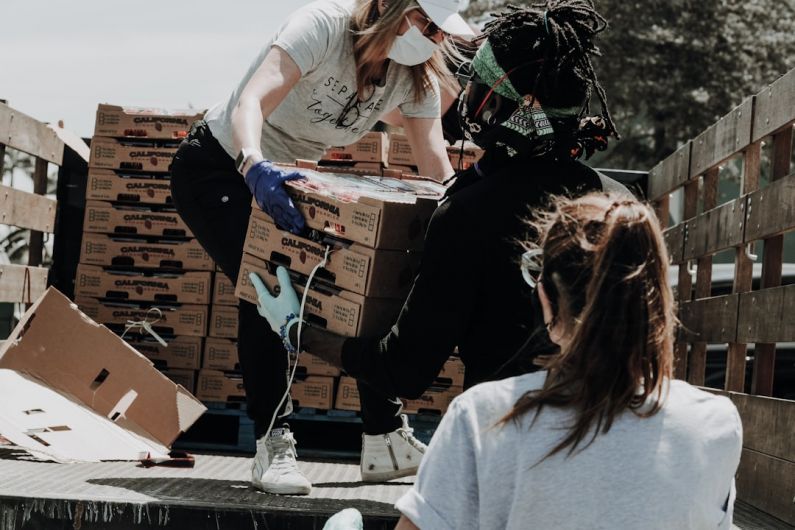 Charity Event - woman in white t-shirt and blue denim jeans sitting on brown cardboard box