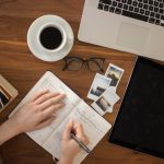 Budget Travel Tips - person holding ballpoint pen writing on notebook