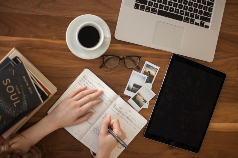 Budget Travel Tips - person holding ballpoint pen writing on notebook