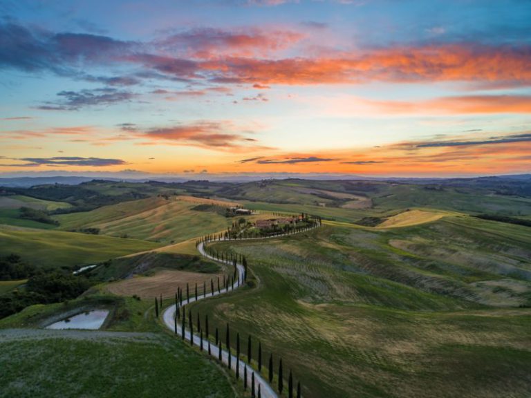 Tuscany Landscape - road between green grass field near mountains under blue and brown sky at golden hour