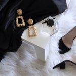 Luxury Bed And Breakfast - pair of gold-colored earrings on table and black ankle-strap pumps on area rug