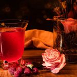 Seasonal Recipes - red liquid in clear drinking glass beside pink rose bouquet