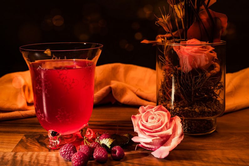 Seasonal Recipes - red liquid in clear drinking glass beside pink rose bouquet