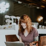Owner At Work - woman sitting on brown wooden chair while using silver laptop computer in room