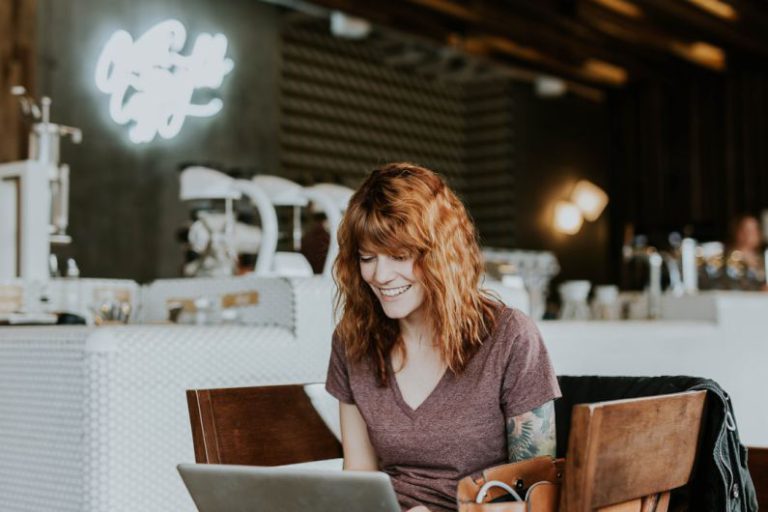 Owner At Work - woman sitting on brown wooden chair while using silver laptop computer in room