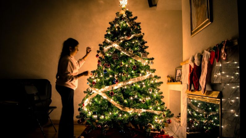 Decorating B&B - child standing in front of Christmas tree with string lights